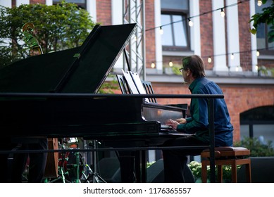 Male Musician On Stage Playing Piano. Crowded Venue. Audience Enjoying Romantic And Relaxing Evening. 
