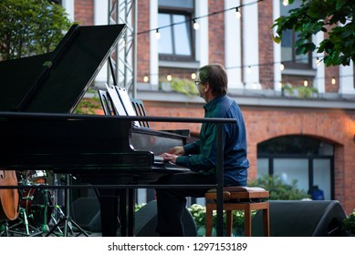 Male Musician On Stage Playing Piano. Crowded Venue. Audience Enjoying Romantic And Relaxing Evening. 
