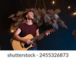 Male musician playing acoustic guitar. Guitarist plays classical guitar on stage in concert Handsome young hipster male guitar player perform private party Stylish long hair Medium shoot