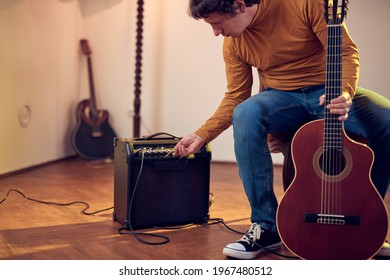 Male Musician Playing Acoustic Guitar On The Amplifier In Retro Vintage Room.