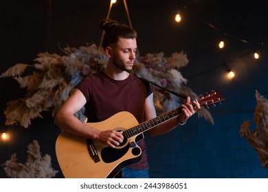 Male musician playing acoustic guitar. Guitarist plays classical guitar on stage in concert Handsome male guitar player perform private party Stylish long hair Medium shoot
