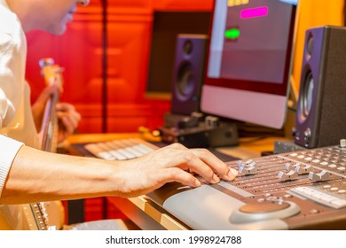 male musician recording electric guitar track on computer, focus on hand. music production concept