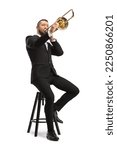 Male musician sitting on a chair and playing a trombone  isolated on white background
