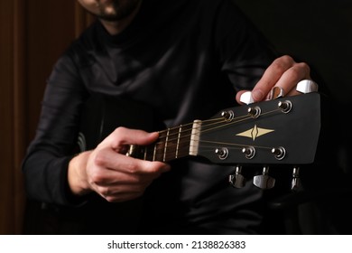 male musician tuning the strings on the guitar