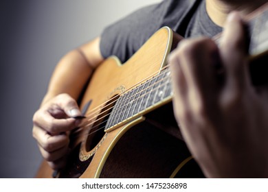 Male musicians playing acoustic guitar. Closeup musicians are playing acoustic guitar. Male musicians hold chords and strum guitar.