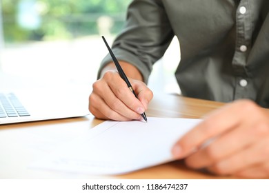 Male notary signing document at table in office, closeup