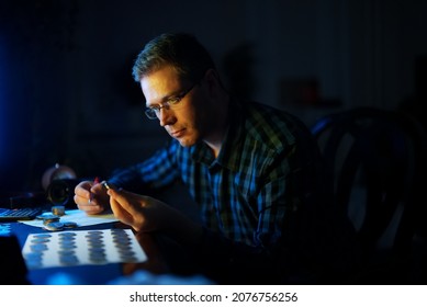 Male Numismatist Examines Collection Of Coins.