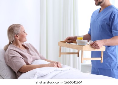 Male Nurse Bringing Food And Medicine For Patient In Hospital Ward. Doctor's Prescription