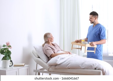 Male Nurse Bringing Food And Medicine For Patient In Hospital Ward. Doctor's Prescription