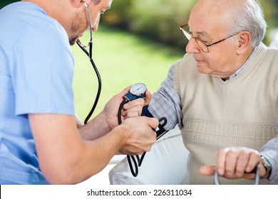 Male Nurse Checking Blood Pressure Of Senior Man At Nursing Home