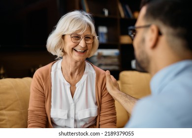 Male Nurse Communicating With Happy Mature Woman At Nursing Home. Focus Is On Woman.