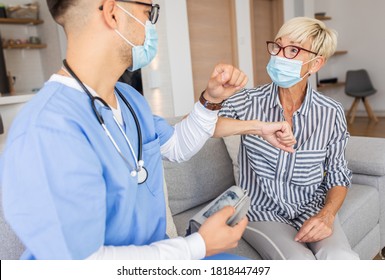 Male Nurse Greeting With Senior Female Patient With Mask While Being In A Home Visit.