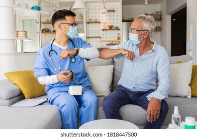 Male Nurse Greeting With Senior Male Patient With Mask While Being In A Home Visit.