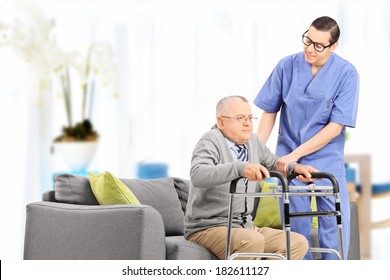 Male nurse helping an elderly gentleman to stand up in a nursing home