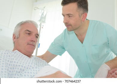 Male Nurse Helping Senior Patient On Bed