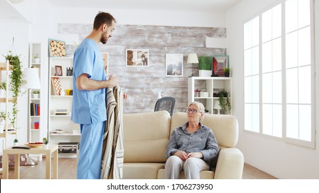 Male Nurse Helping Senior Woman Getting Dressed In Nursing Home