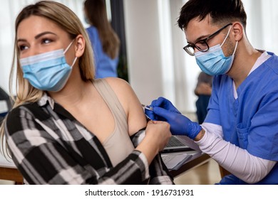 Male Nurse With Mask Giving Vaccine To Patient In Clinic.