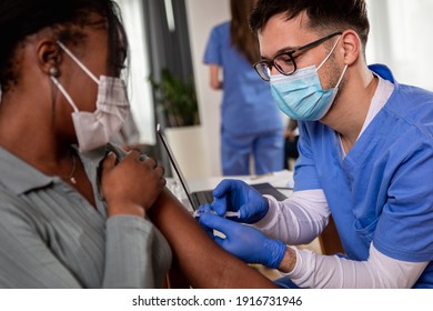 Male nurse with mask giving vaccine to patient in clinic. - Powered by Shutterstock