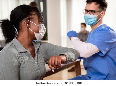 Male nurse with mask greeting with patient in clinic.