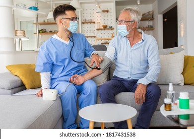 Male Nurse Measures Blood Pressure To Senior Man With Mask While Being In A Home Visit.