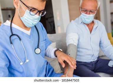 Male Nurse Measures Blood Pressure To Senior Man With Mask While Being In A Home Visit.