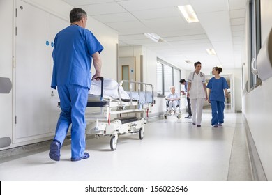 Male nurse pushing stretcher gurney bed in hospital corridor with doctors & senior female patient - Shutterstock ID 156022646