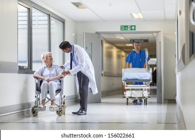 Male nurse pushing stretcher gurney bed in hospital corridor with doctor & senior female patient - Powered by Shutterstock