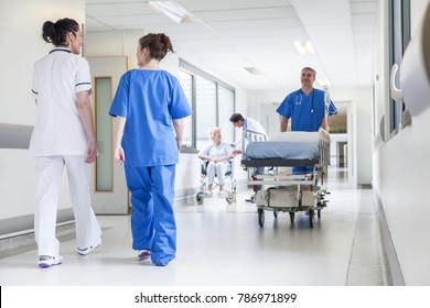 Male nurse pushing stretcher gurney bed in hospital corridor with doctors & senior female patient - Shutterstock ID 786971899