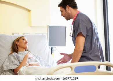 Male Nurse Talking With Female Patient In Hospital Room