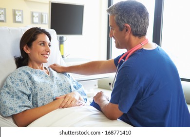 Male Nurse Talking With Female Patient In Hospital Room