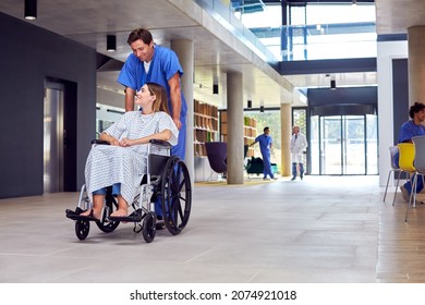 Male Nurse Wearing Scrubs Pushing Female Patient In Wheelchair Through Hospital Building - Powered by Shutterstock