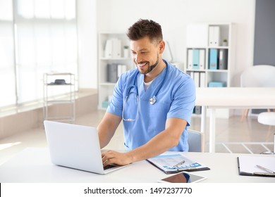 Male Nurse Working On Laptop In Clinic