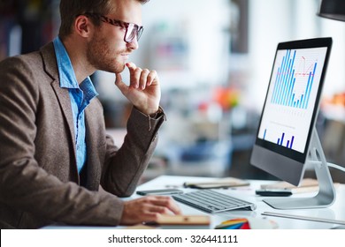 Male Office Worker Looking At Computer Screen With Data