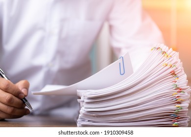 Male office workers holding and writing documents on office desk with light fair, Stack of business overload paper.