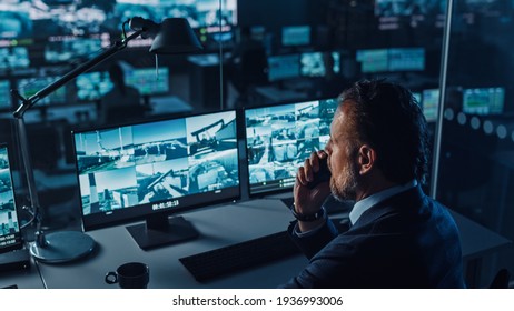 Male Officer Works on a Computer with Surveillance CCTV Video in a Harbour Monitoring Center with Multiple Cameras on a Big Digital Screen. Employee Uses Radio to Give an Order or Report. - Shutterstock ID 1936993006