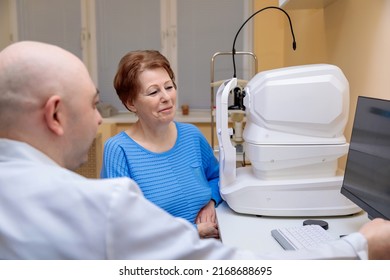 A Male Ophthalmologist Explains The Results Of An Eye Examination To An Adult Woman, Showing A Drawing On A Computer.