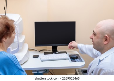 A Male Ophthalmologist Explains The Results Of An Eye Examination To An Adult Woman, Showing A Drawing On A Computer.