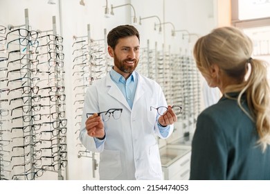 Male optician showing glasses to woman at optics store