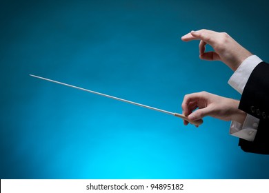 Male Orchestra Conductor Hands, One With Baton. Blue Background.