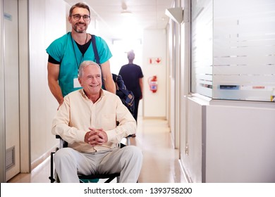 Male Orderly Pushing Senior Male Patient Being Discharged From Hospital In Wheelchair