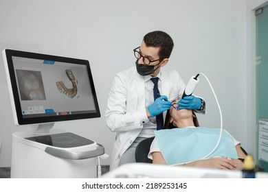 Male orthodontist scaning patient with dental intraoral scanner and controls process on screen. Prosthodontics and stomatology concept. - Powered by Shutterstock