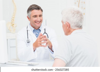 Male Orthopedic Doctor Discussing With Senior Patient In Clinic