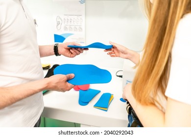 Male orthopedist checking patient's foot in clinicThe orthopedist offers the insole to the patient
