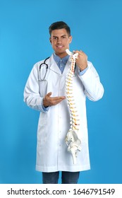 Male Orthopedist With Human Spine Model Against Blue Background