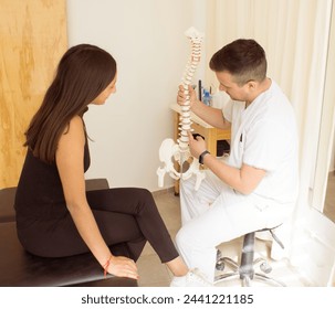 
A male osteopath explaining to his female patient about a lumbar disc herniation with a spine model. Medical consultation for spinal pain. - Powered by Shutterstock