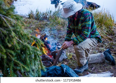 A Male Outdoorsman Building A Campfire At His Remote Shelter - Powered by Shutterstock