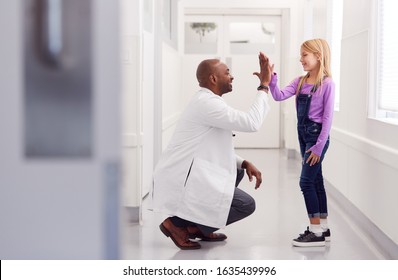 Male Paediatric Doctor Giving Young Girl Patient High Five In Hospital Corridor - Powered by Shutterstock