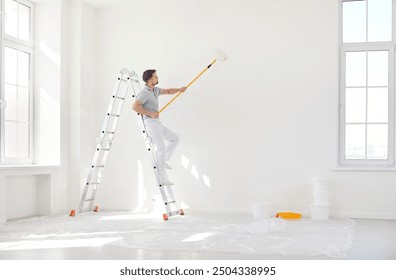 Male painter or construction worker painting wall surface in white color with paint roller brush, service man on stepladder finishing task for room, building repair, interior architecture and design  - Powered by Shutterstock