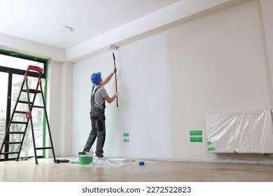 Male painter paints house wall with roller brush. Decoration and improvement interior concept. - Powered by Shutterstock