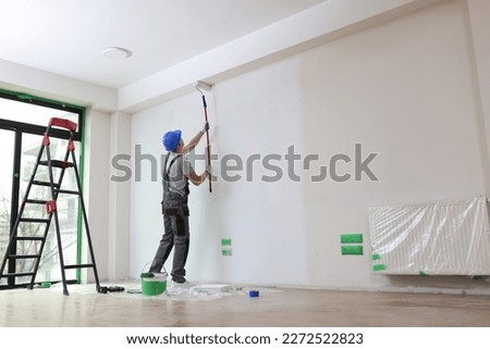 Male painter paints house wall with roller brush. Decoration and improvement interior concept.